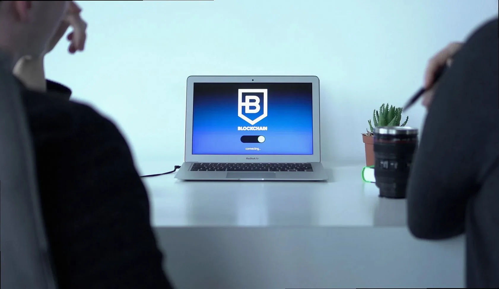 Colleagues discussing blockchain technology with a laptop in a modern office setting.